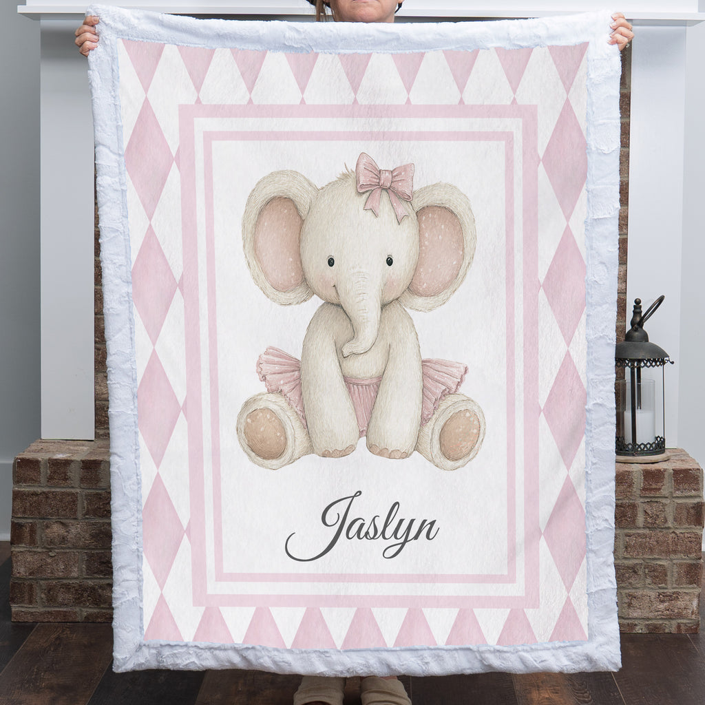Personalized elephant minky baby blanket with tutu design, held up by fireplace mantel