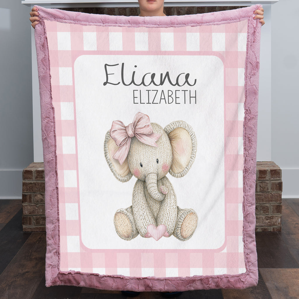 Personalized elephant minky baby blanket with mauve fur trim, held up by fireplace