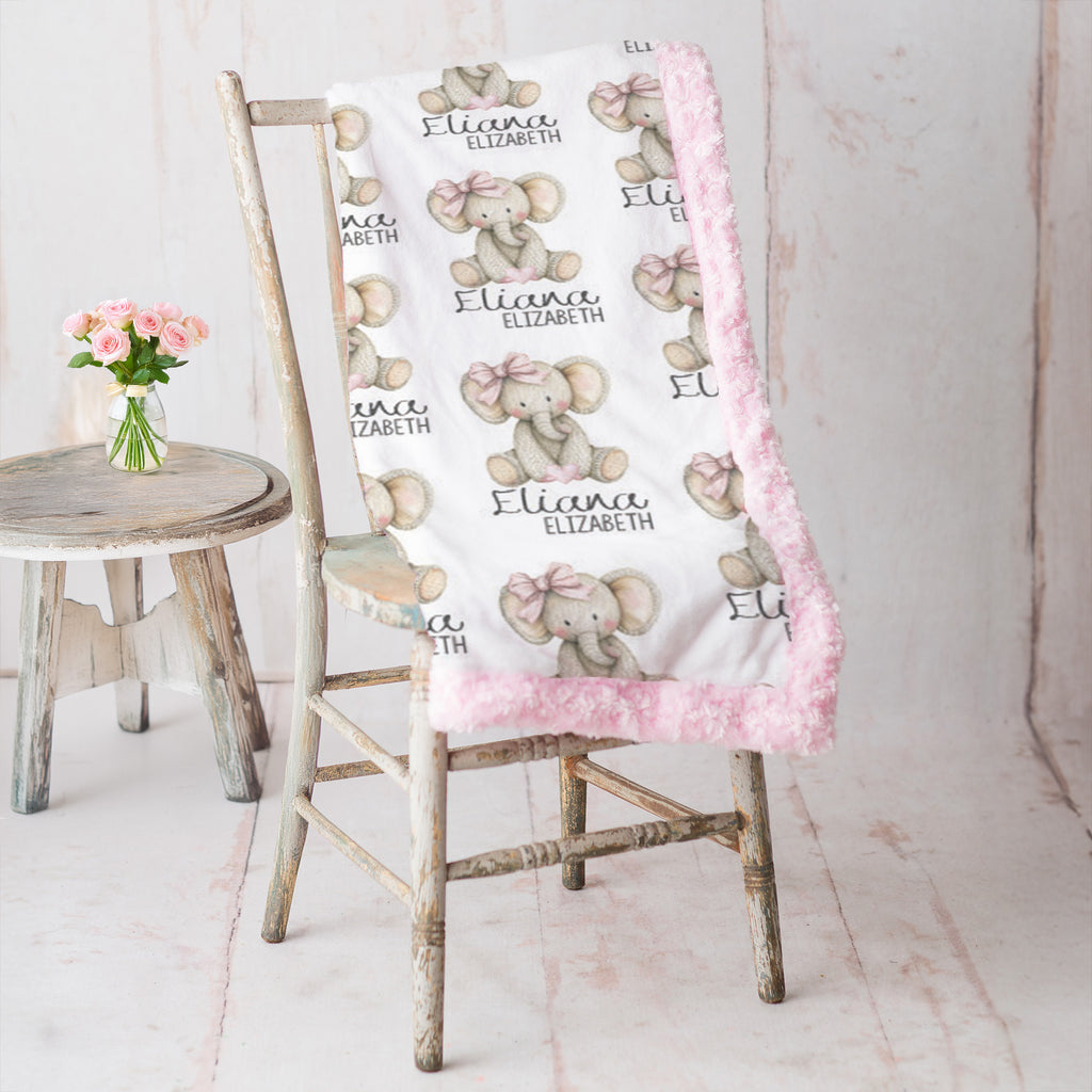Woman holding personalized elephant baby blanket with pink minky trim by fireplace mantel
