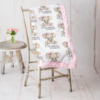 Woman holding personalized elephant baby blanket with pink minky trim by fireplace mantel