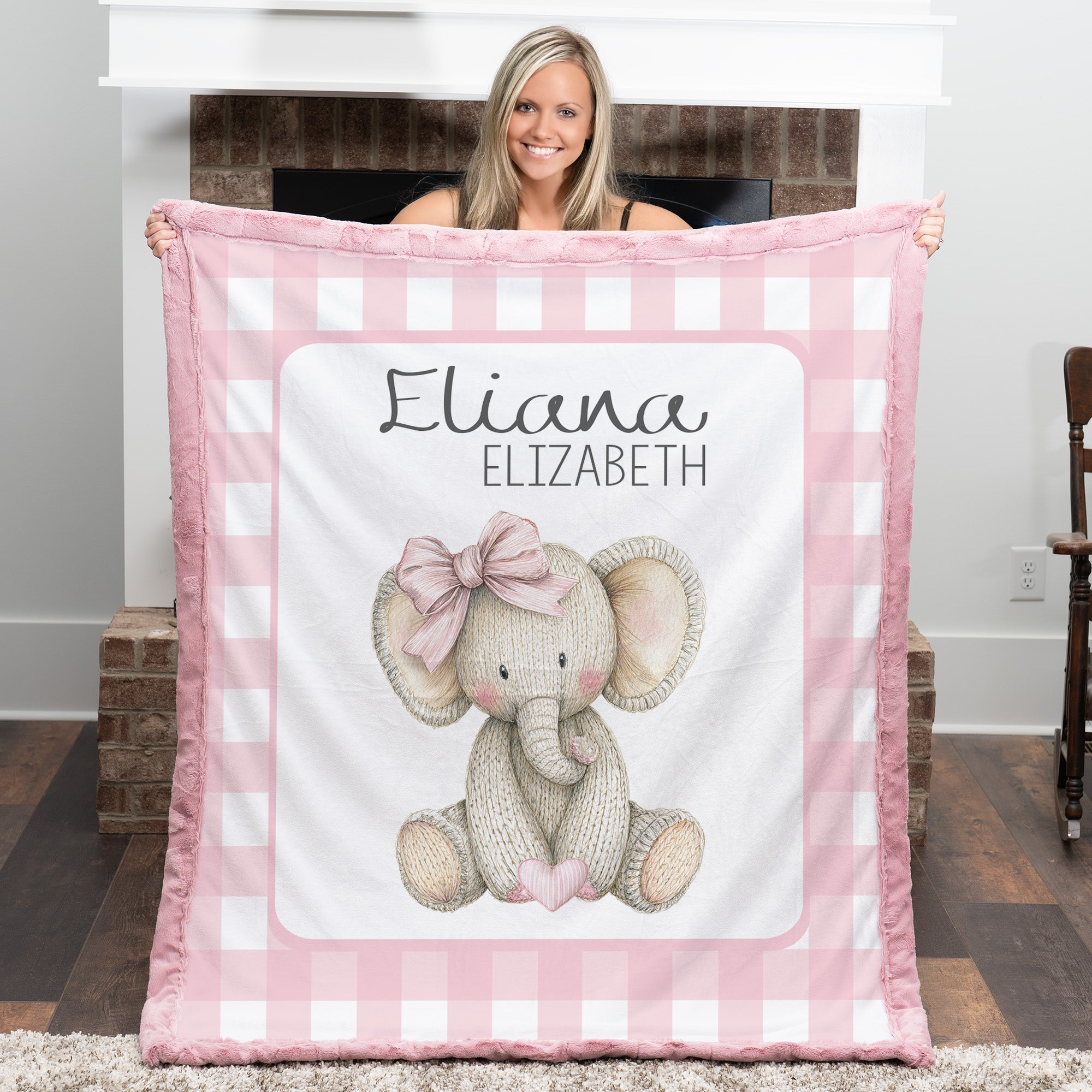 Personalized elephant minky baby blanket with pink fur trim, held up by fireplace