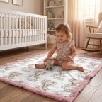 Toddler playing with elephant toy on personalized elephant baby blanket with pink trim