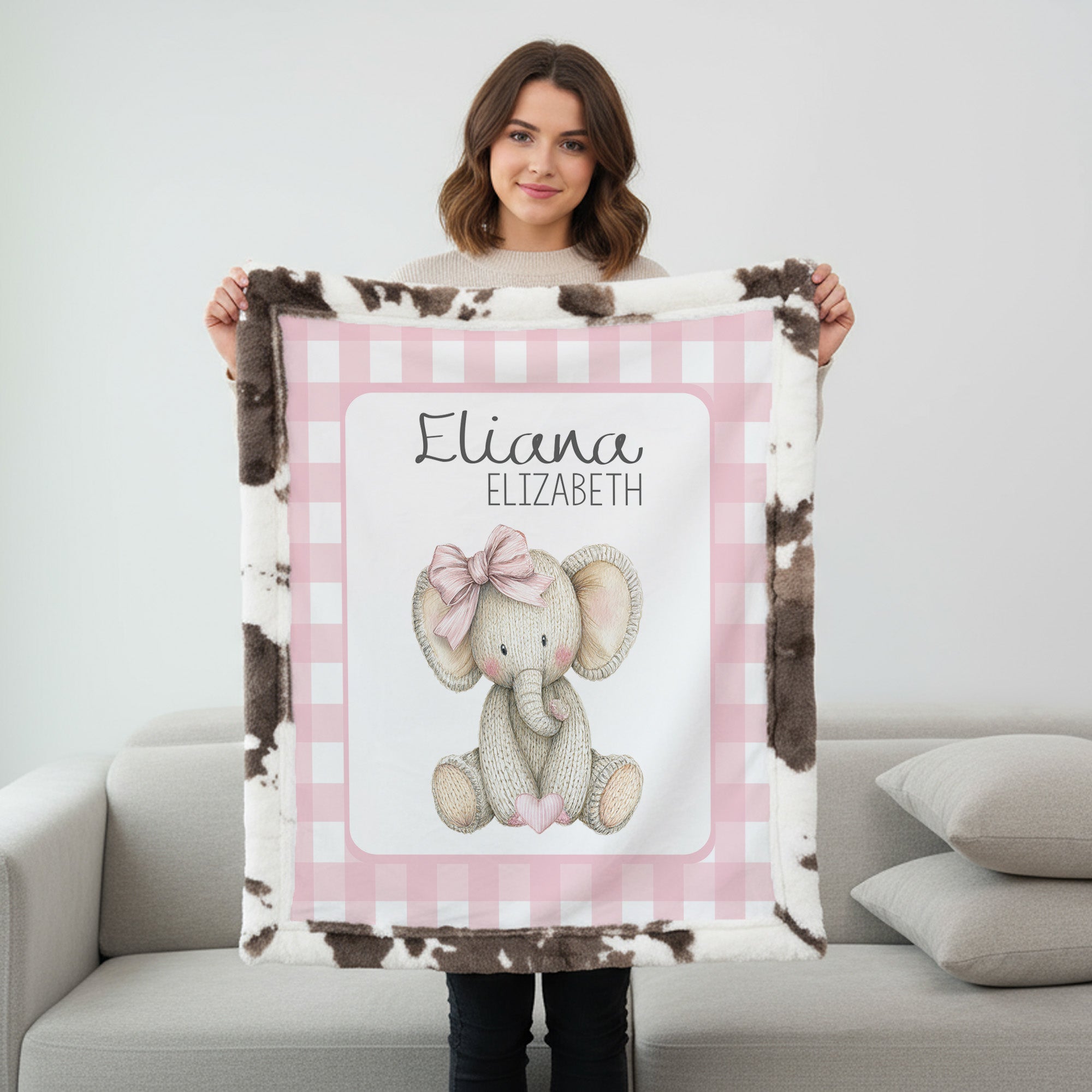 Personalized elephant minky baby blanket with cow print fur backing, held up indoors