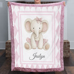 Personalized elephant minky baby blanket with mauve fur trim, held up by fireplace