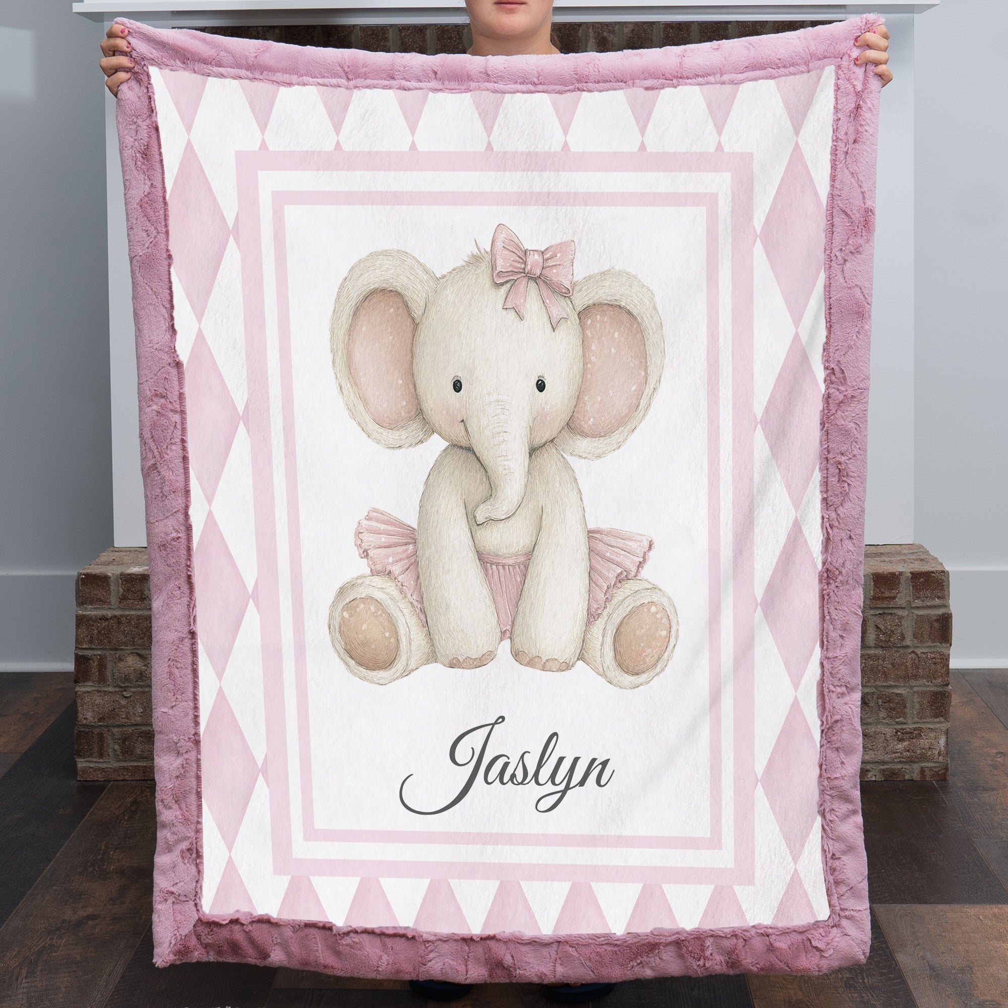 Personalized elephant minky baby blanket with mauve fur trim, held up by fireplace
