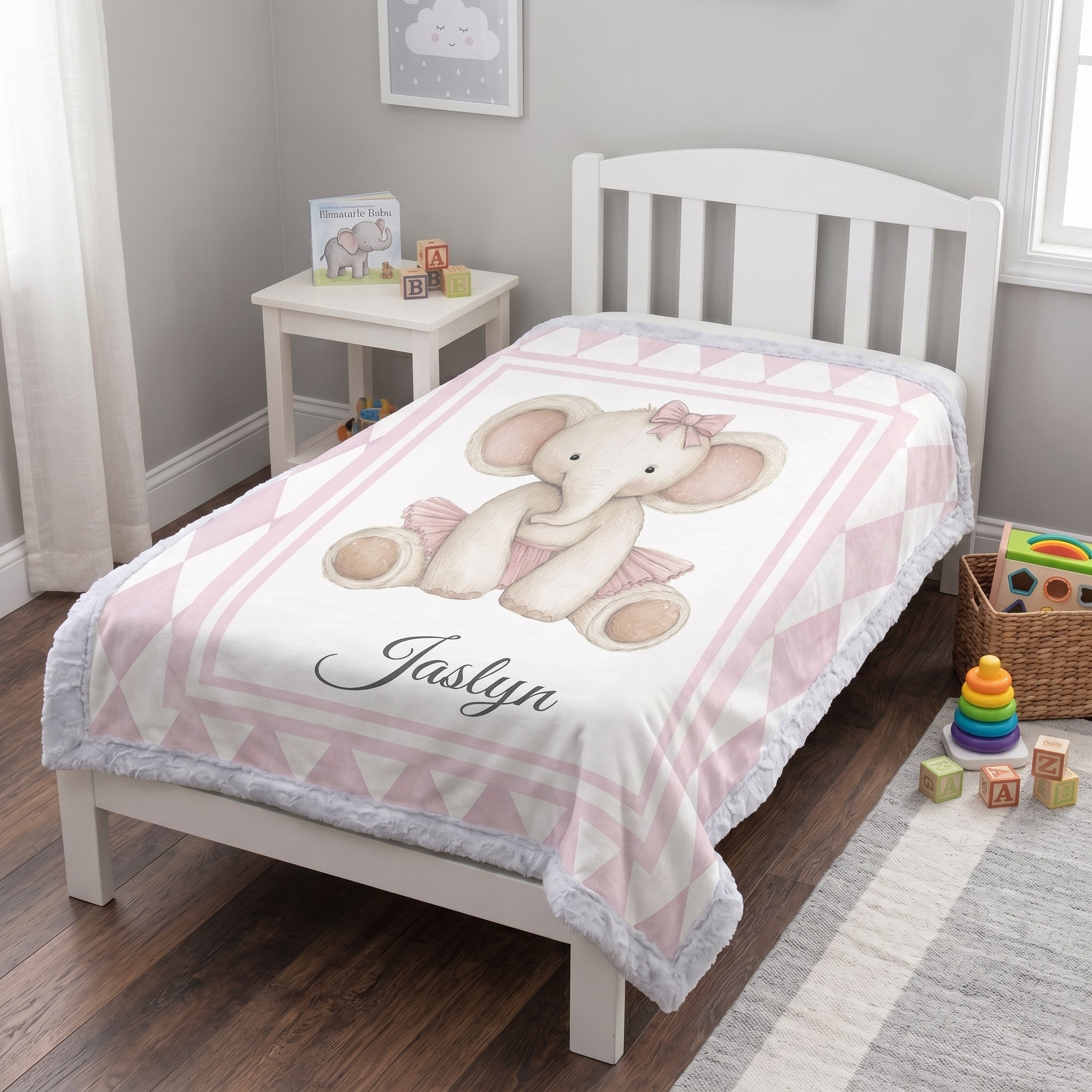 Personalized elephant minky blanket laid flat on toddler bed with toys nearby
