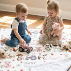 Toddler sitting on personalized farm animal minky blanket surrounded by toys