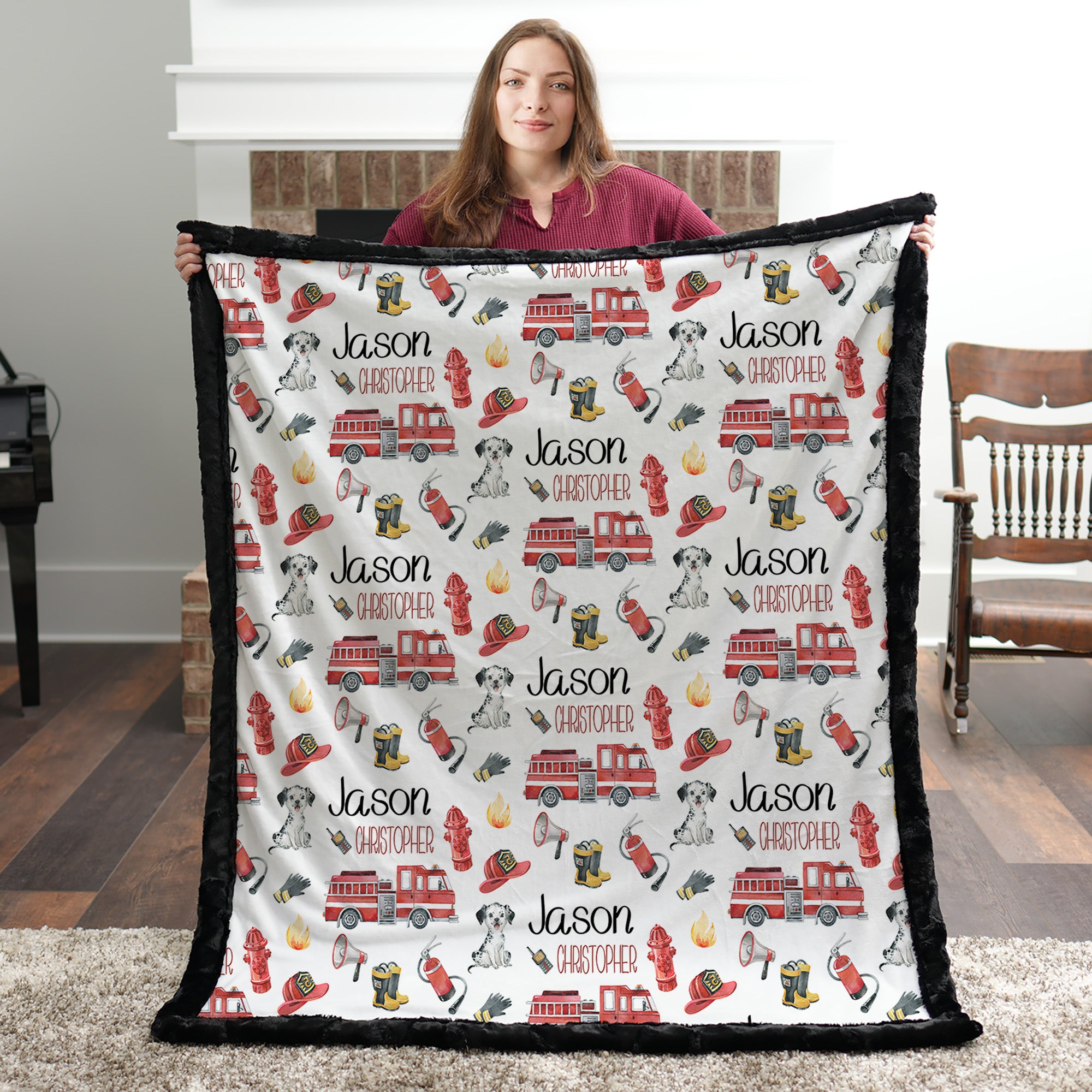 Personalized firefighter baby blanket with black faux fur border, held by woman in front of fireplace