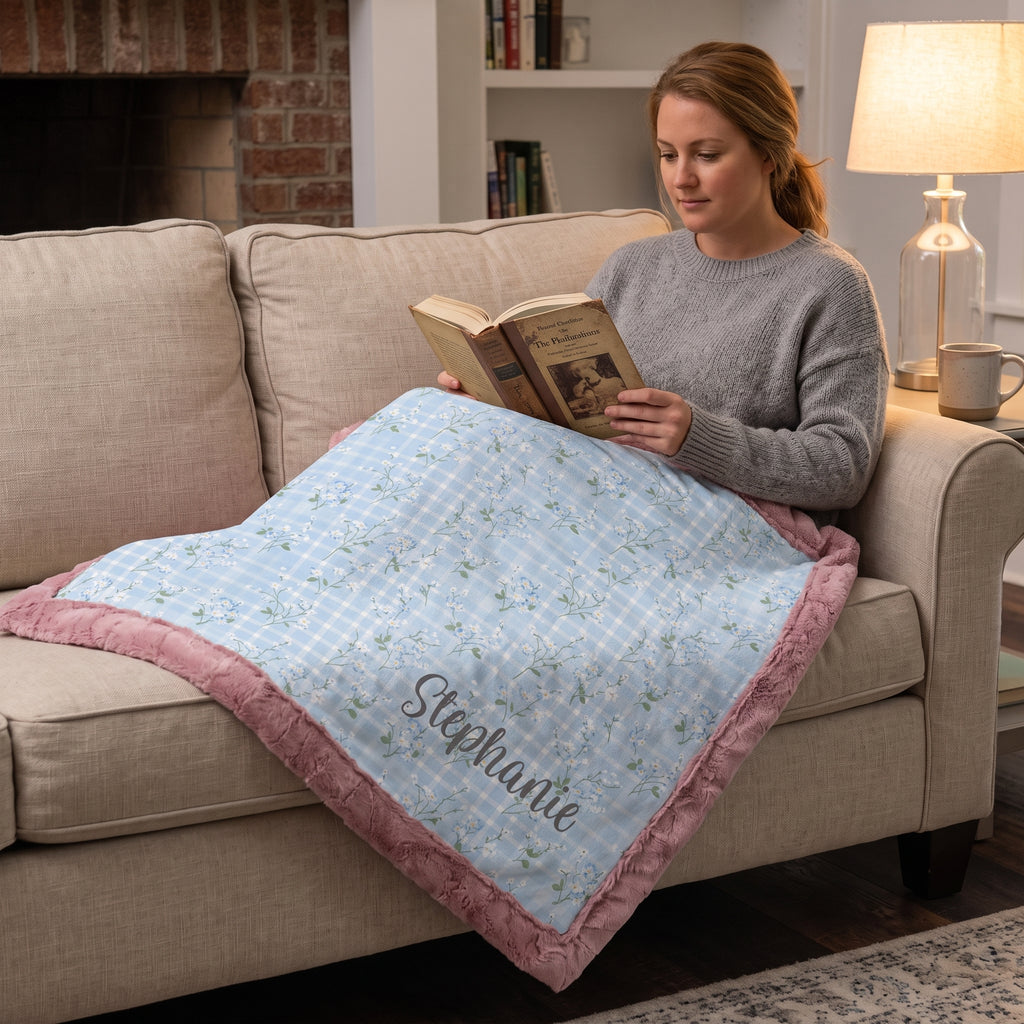 Woman reading with personalized floral gingham Luxe Cuddle blanket with pink trim on her lap