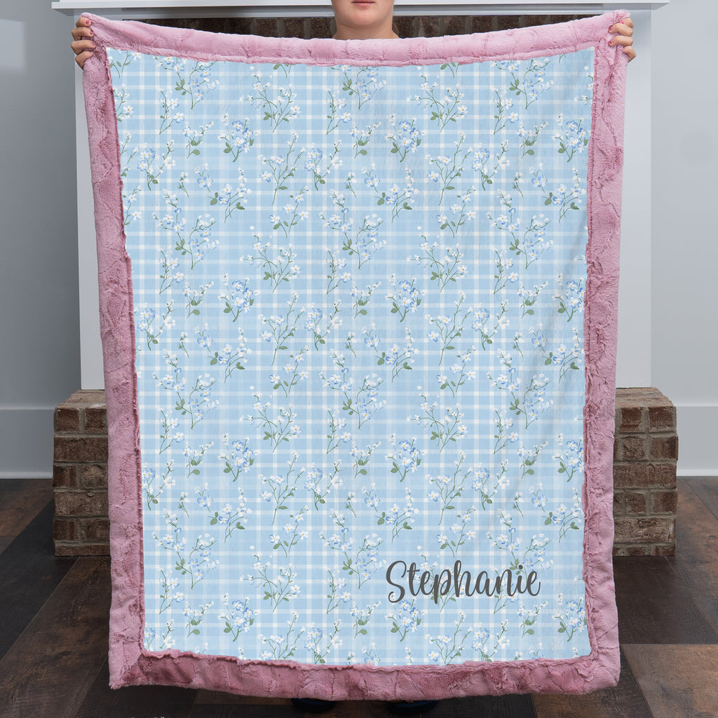 Personalized floral gingham Luxe Cuddle blanket with pink trim held up by two people