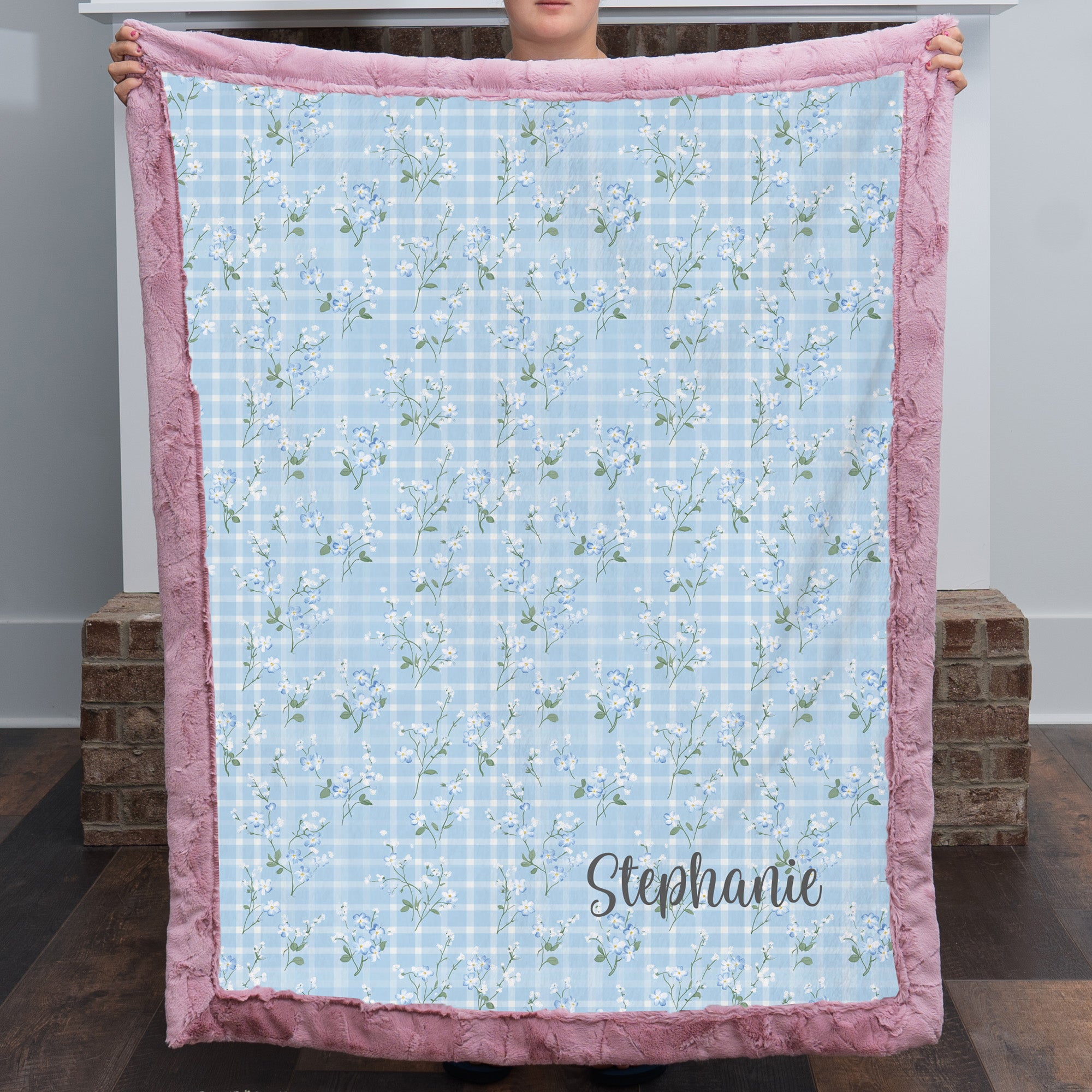 Personalized floral gingham Luxe Cuddle blanket with pink trim held up by two people