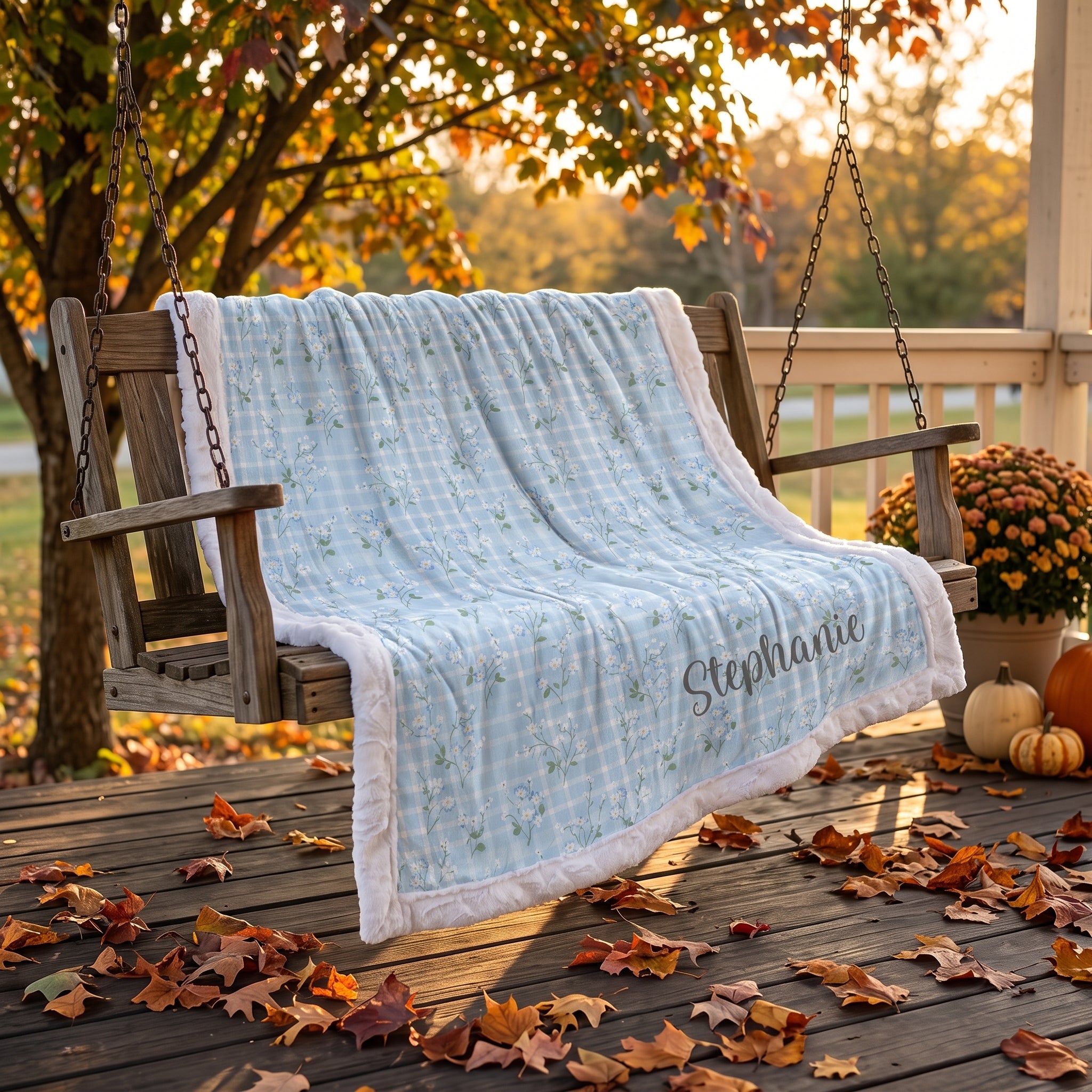 Personalized floral gingham Luxe Cuddle blanket with white trim draped on porch swing in fall