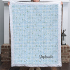 Personalized floral gingham Luxe Cuddle blanket with white trim held up indoors