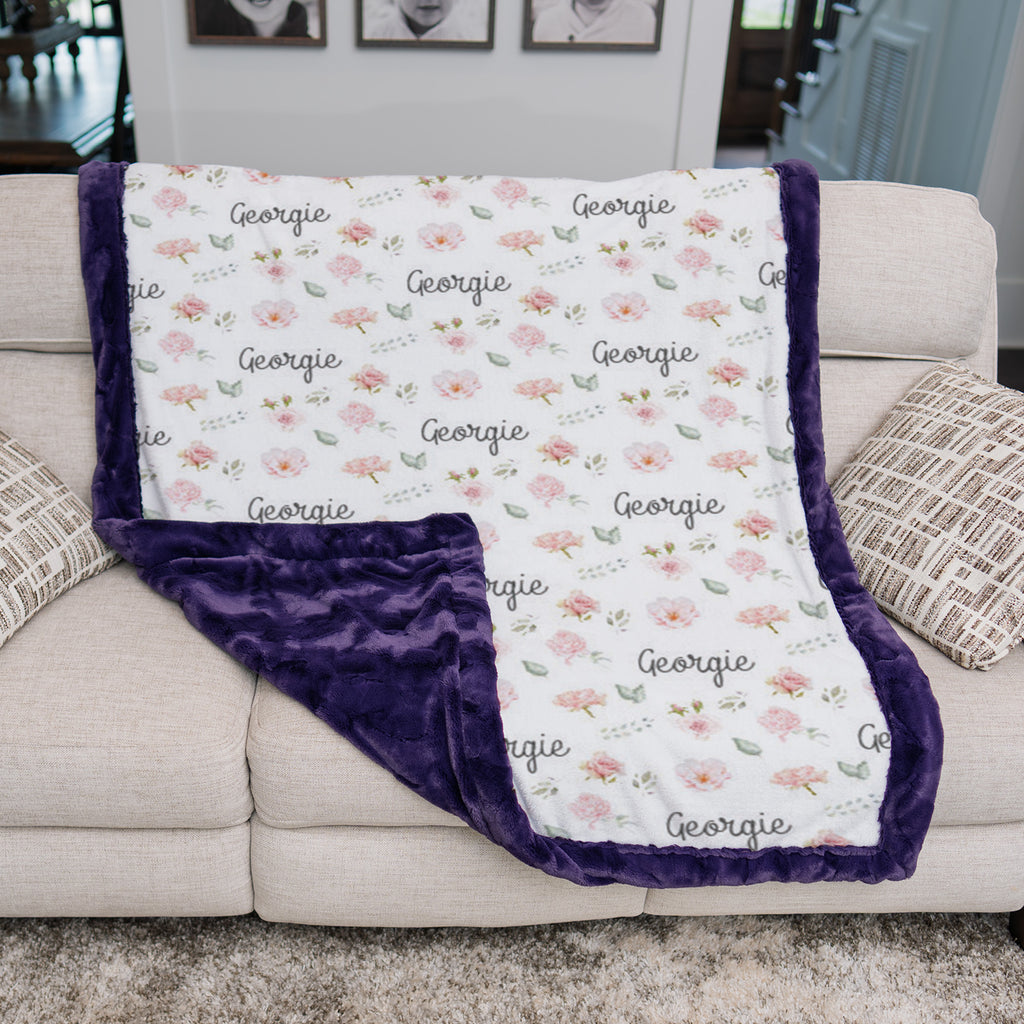 Personalized floral keepsake blanket folded over couch showing purple satin backing