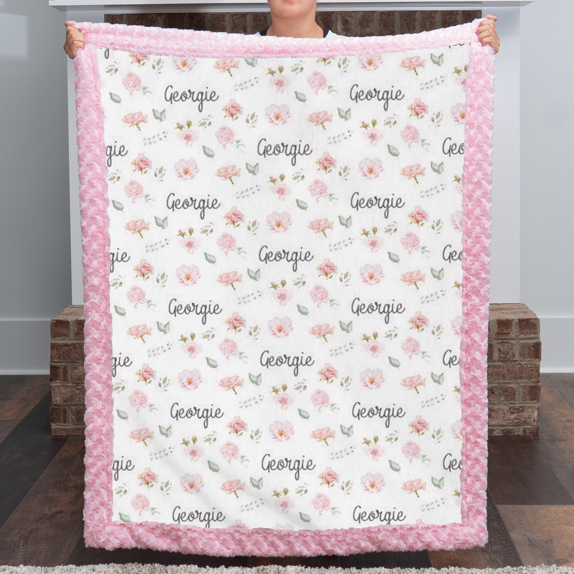 Woman holding personalized floral minky blanket with custom name, pink rosette faux fur trim