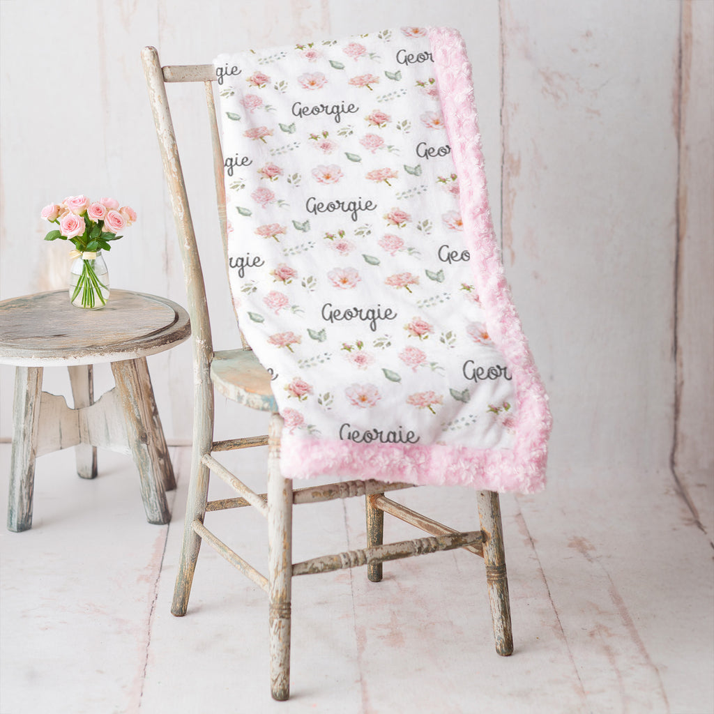 Personalized floral minky blanket draped over vintage chair, pink rosette faux fur trim
