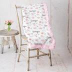 Personalized floral minky blanket draped over vintage chair, pink rosette faux fur trim