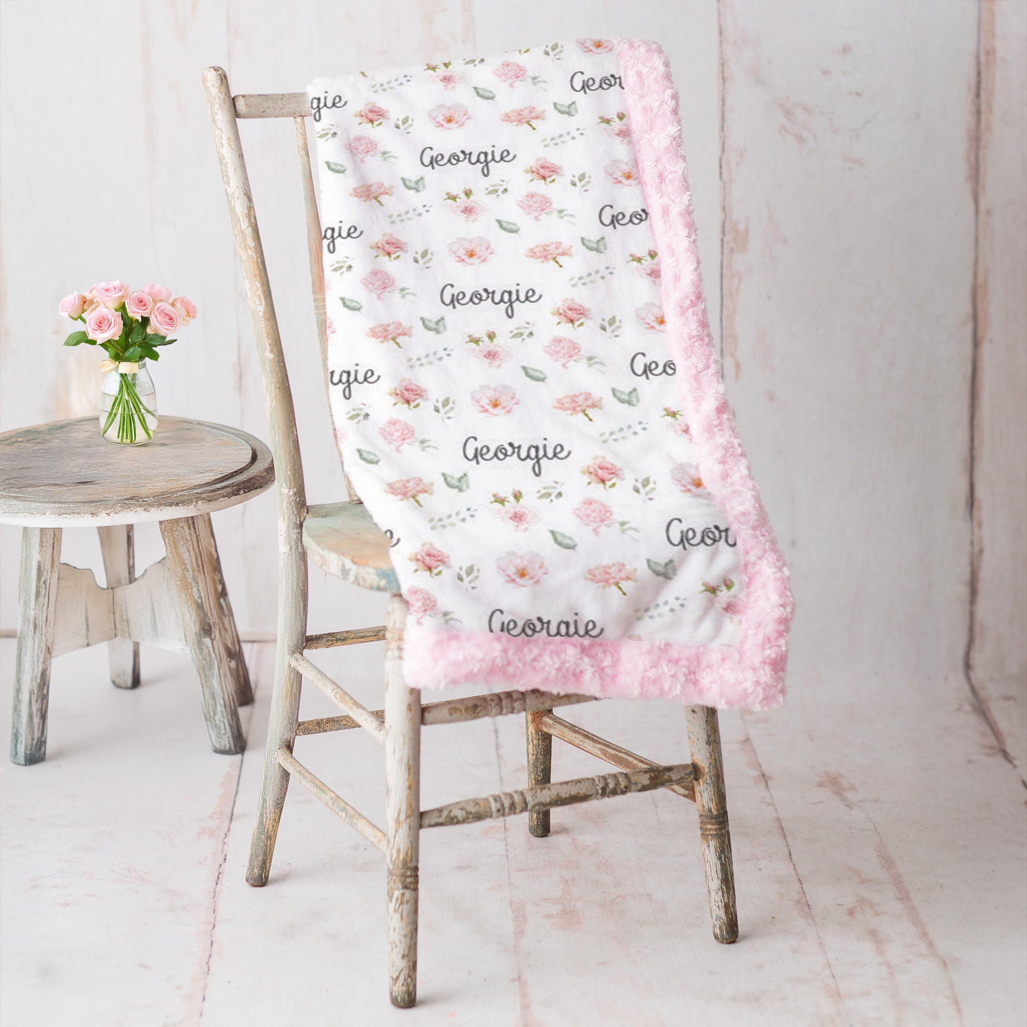 Personalized floral minky blanket draped over vintage chair, pink rosette faux fur trim