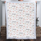 Woman holding personalized floral minky blanket with custom name by fireplace, white trim