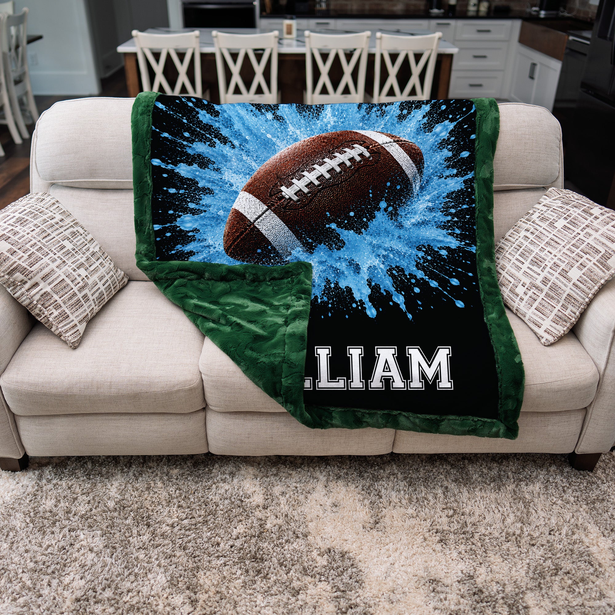 Personalized football blanket folded on couch, showing blue minky front and green minky back