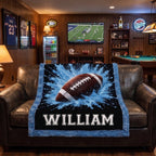 Personalized football minky baby blanket draped over leather chairs in a man cave with football on TV