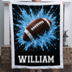 Personalized football minky baby blanket with white trim and name William, held near a fireplace