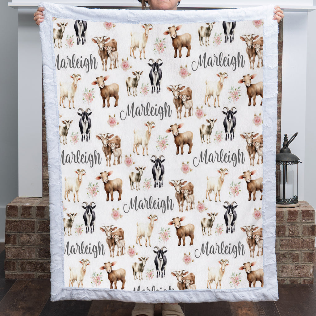 Personalized goat and floral minky baby blanket with name held up by a fireplace