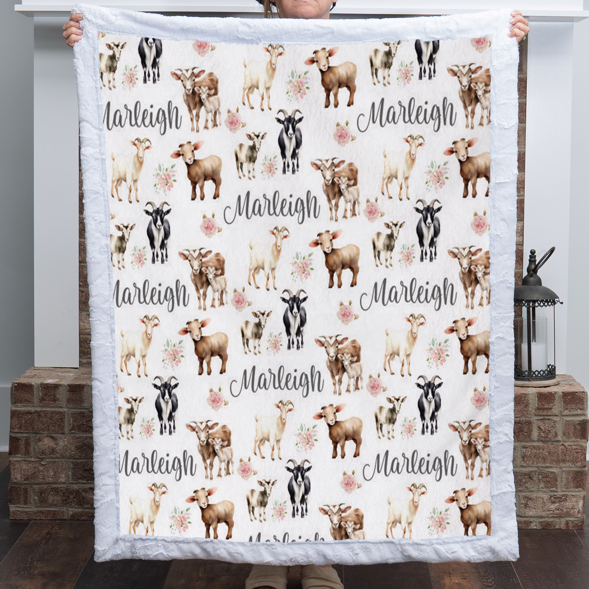 Personalized goat and floral minky baby blanket with name held up by a fireplace