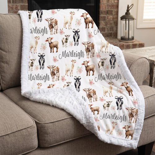 Personalized goat and floral minky baby blanket draped over armchair by a fireplace