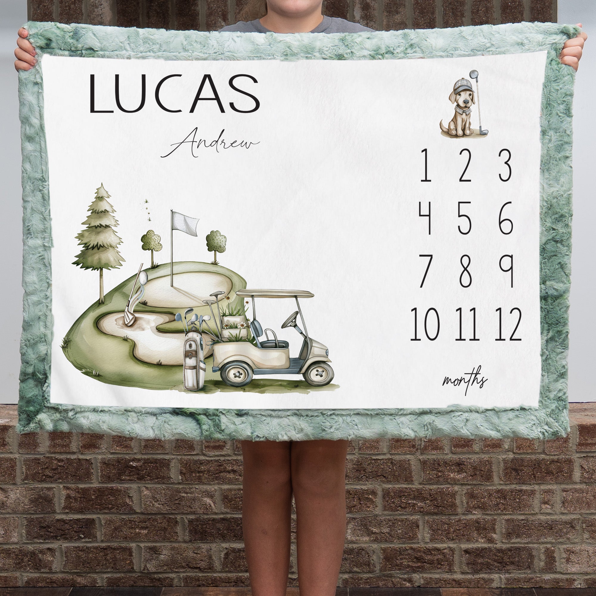 Personalized golf milestone baby blanket with sage faux fur border, held by child against brick wall
