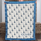 Child holding personalized golf-print minky blanket with name Oliver, blue trim, by fireplace