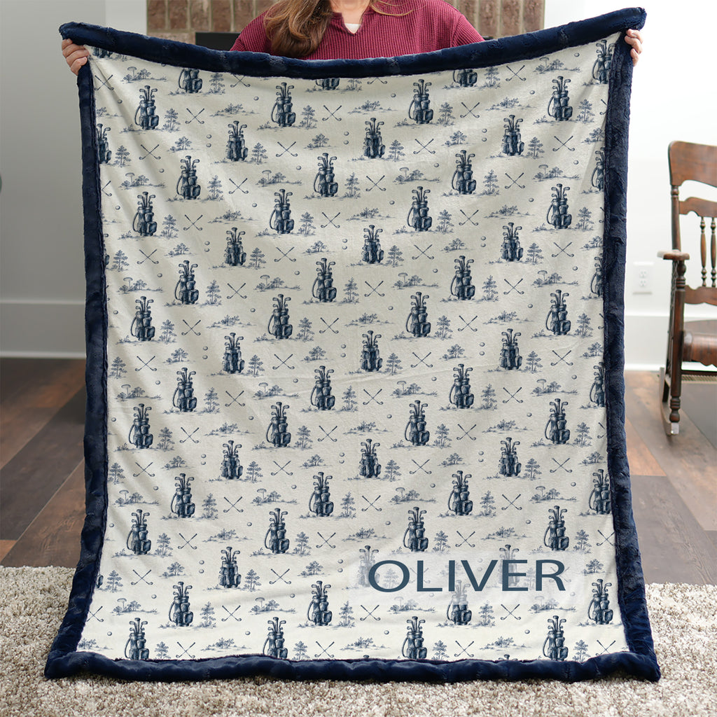 Woman holding personalized golf-print minky blanket with name Oliver, navy trim, indoors