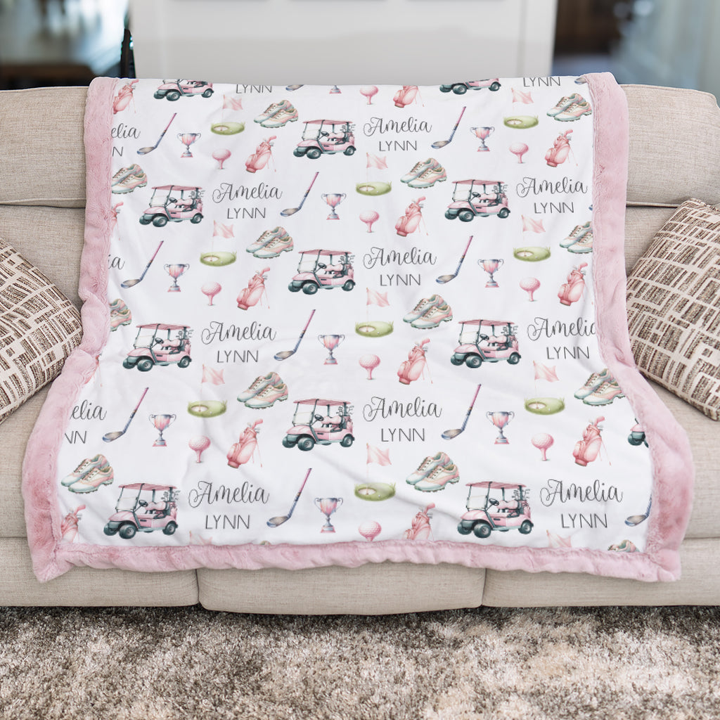Personalized golf minky blanket with pink trim draped over couch