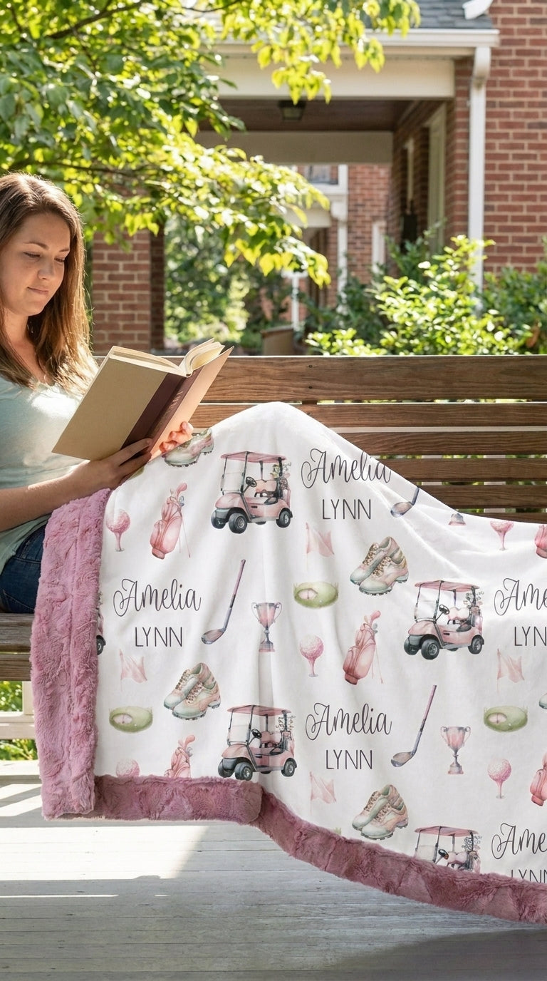 Woman reading on porch bench with personalized golf minky blanket, pink trim