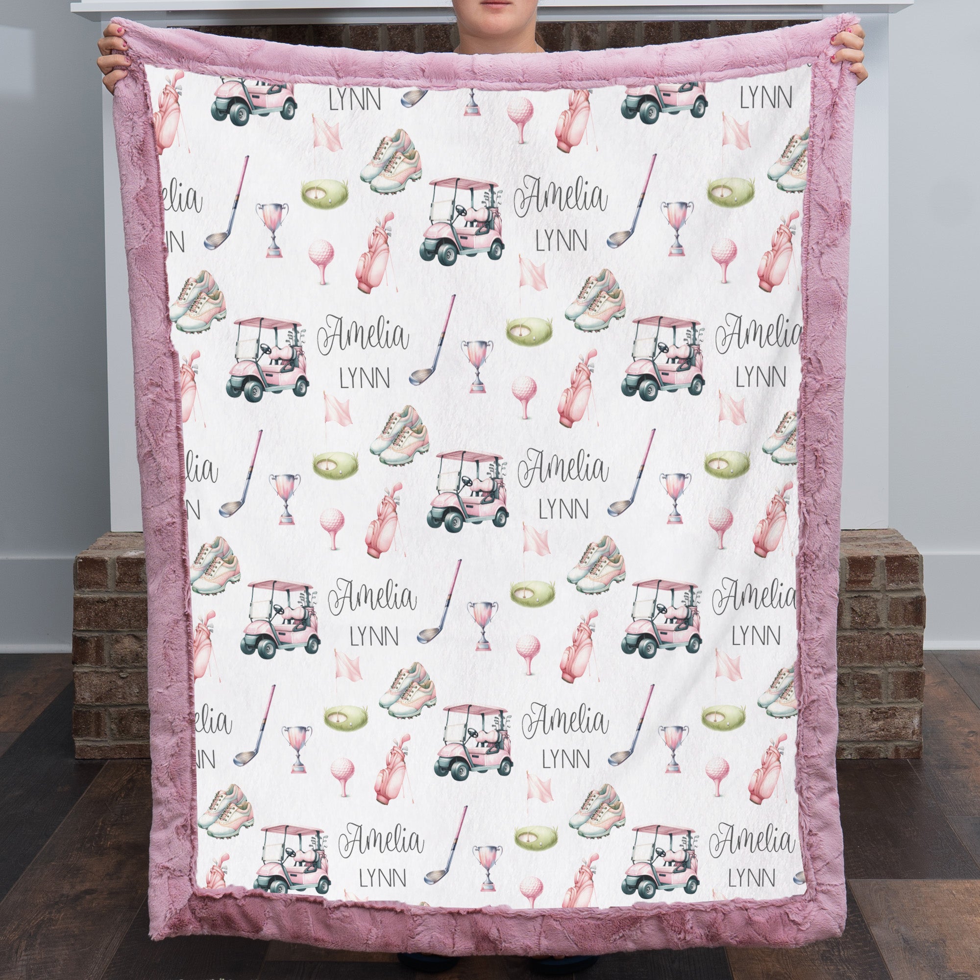 Woman holding personalized golf minky blanket with pink trim indoors