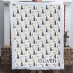 Woman holding personalized golf-print minky blanket with name Oliver, white trim, by fireplace
