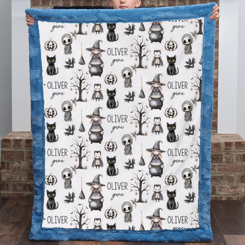 Boy holding personalized Halloween minky blanket with witch, cat, and ghost design, blue trim