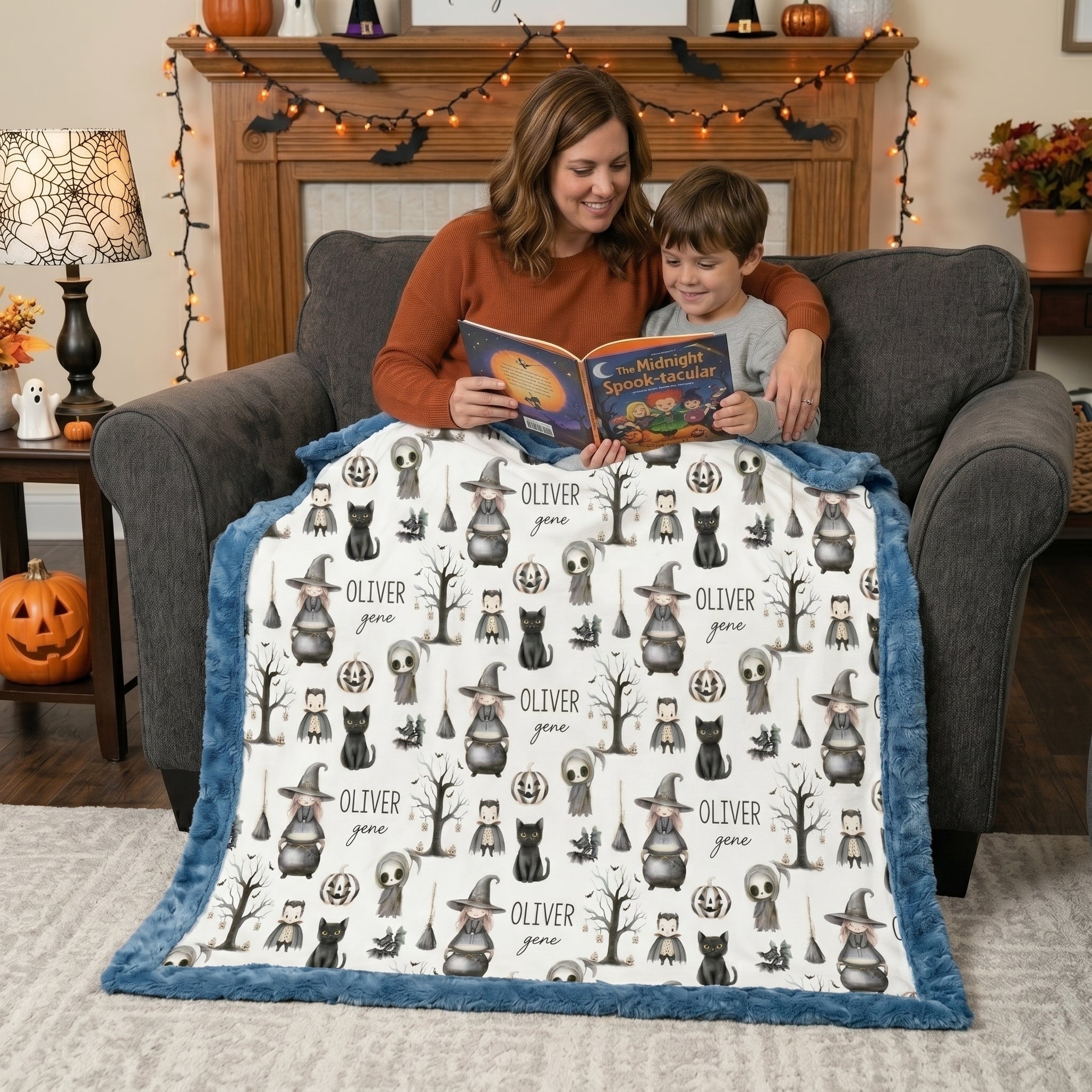 Mother and son reading a Halloween book under personalized minky blanket with blue trim on armchair