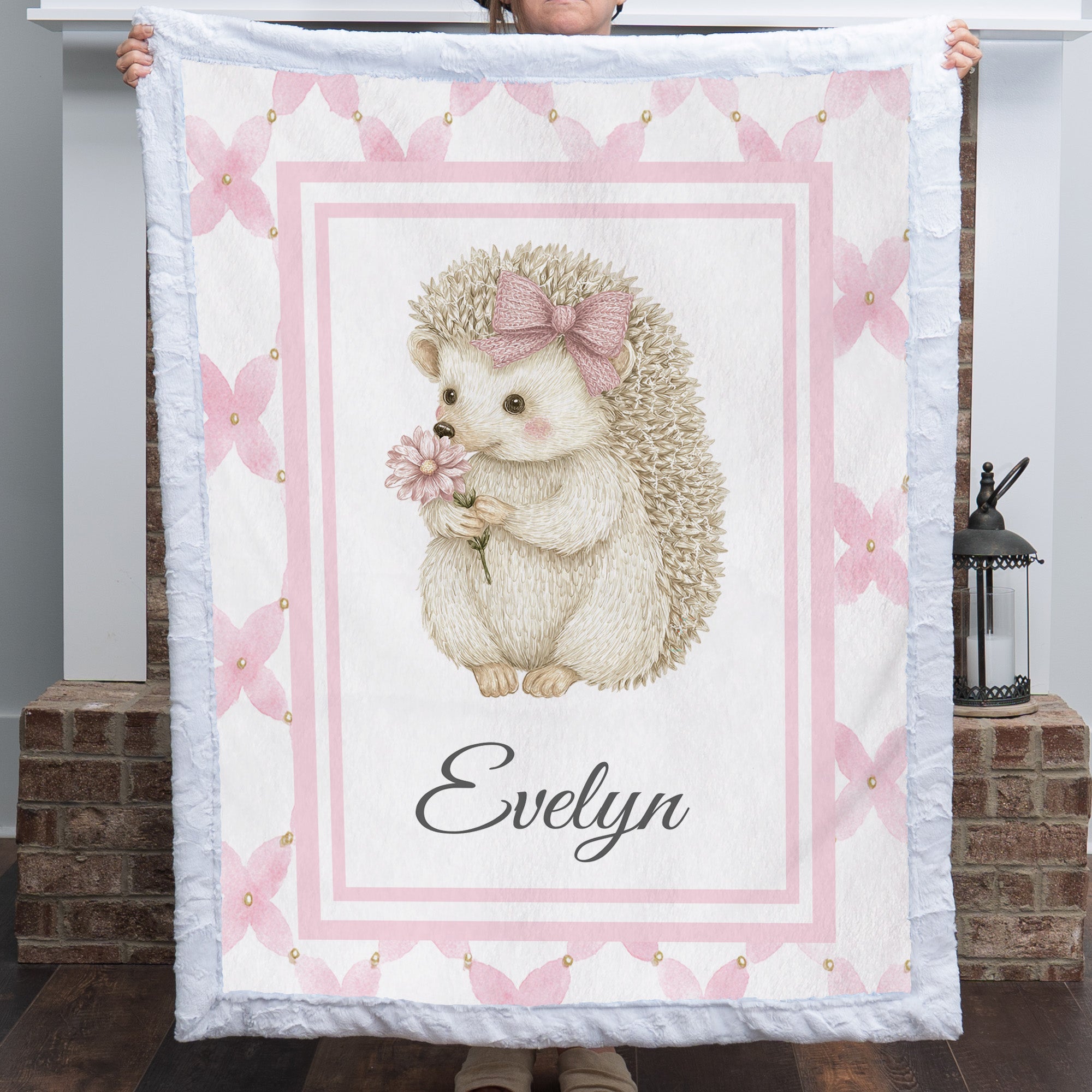 Personalized Luxe Cuddle Minky baby blanket with hedgehog and flower design, held by fireplace