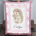 Personalized Luxe Cuddle Minky hedgehog baby blanket held up fully open showing Evelyn name and pink border