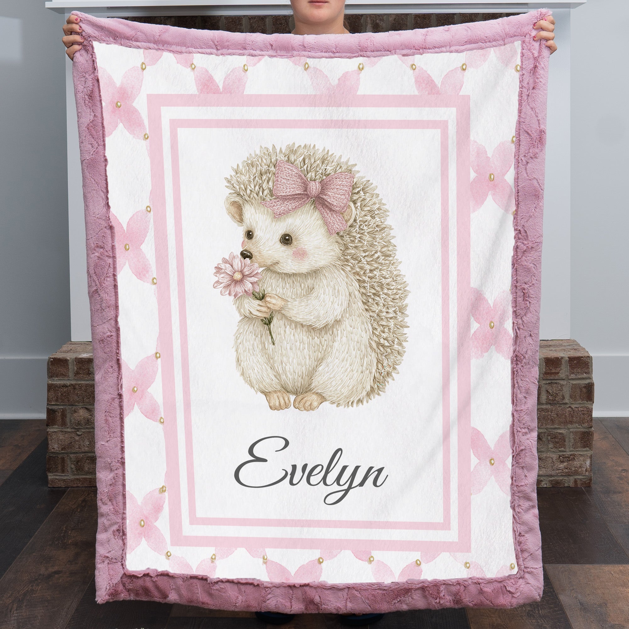 Personalized Luxe Cuddle Minky hedgehog baby blanket held up fully open showing Evelyn name and pink border