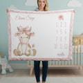 Woman holding personalized highland cow milestone baby blanket with custom name, pink faux fur trim