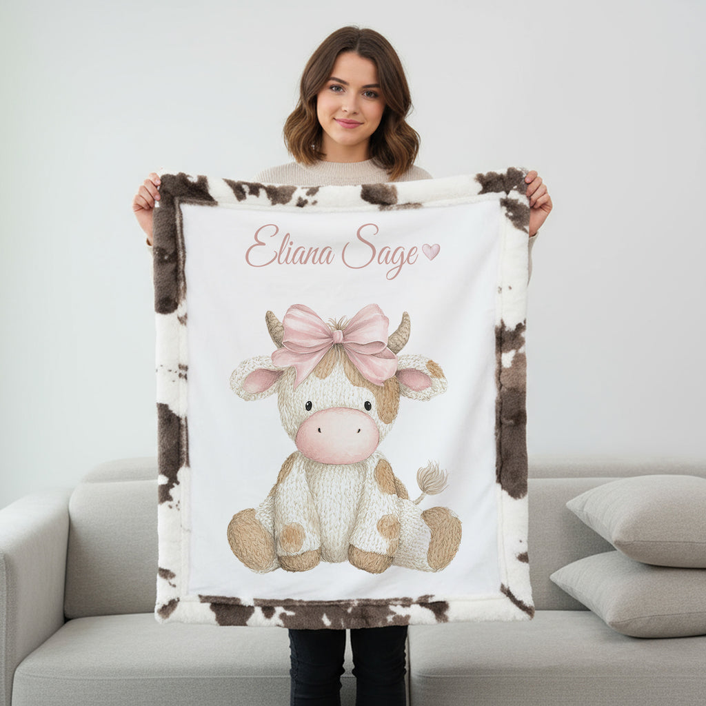 Woman holding personalized highland cow minky blanket with cow print trim on couch