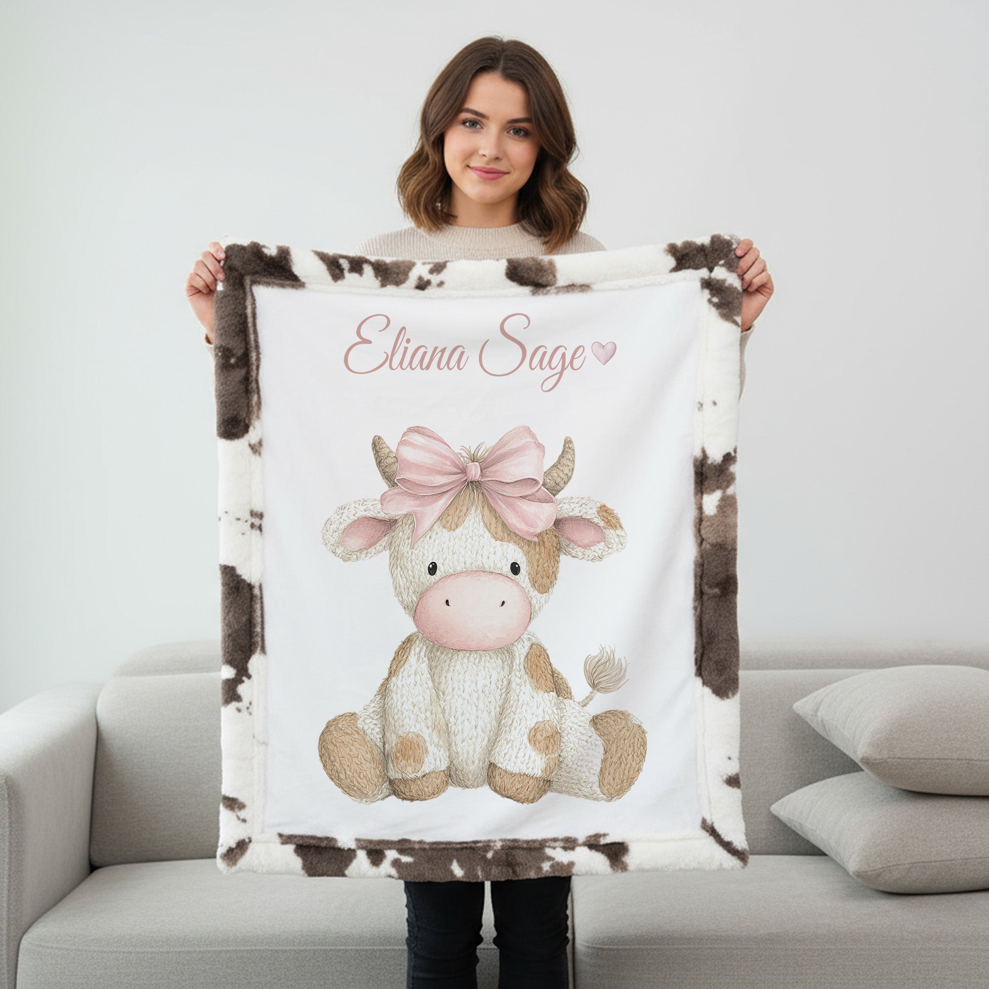 Woman holding personalized highland cow minky blanket with cow print trim on couch