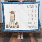 Boy holding personalized horse milestone blanket with custom name by fireplace