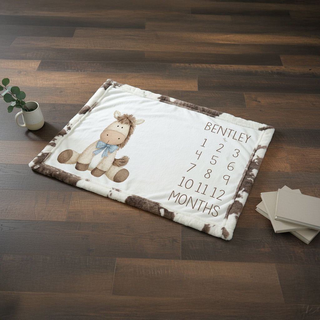 Personalized horse milestone blanket flat lay on wood floor, cow print faux fur trim