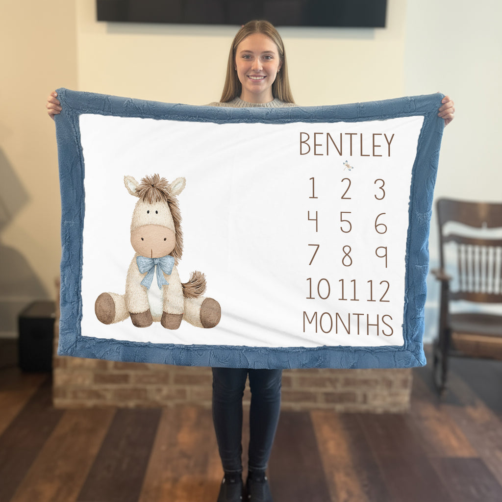 Woman holding personalized horse milestone blanket with custom name, blue faux fur trim