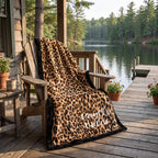 Personalized leopard print minky blanket with black trim draped over chair at lake cabin