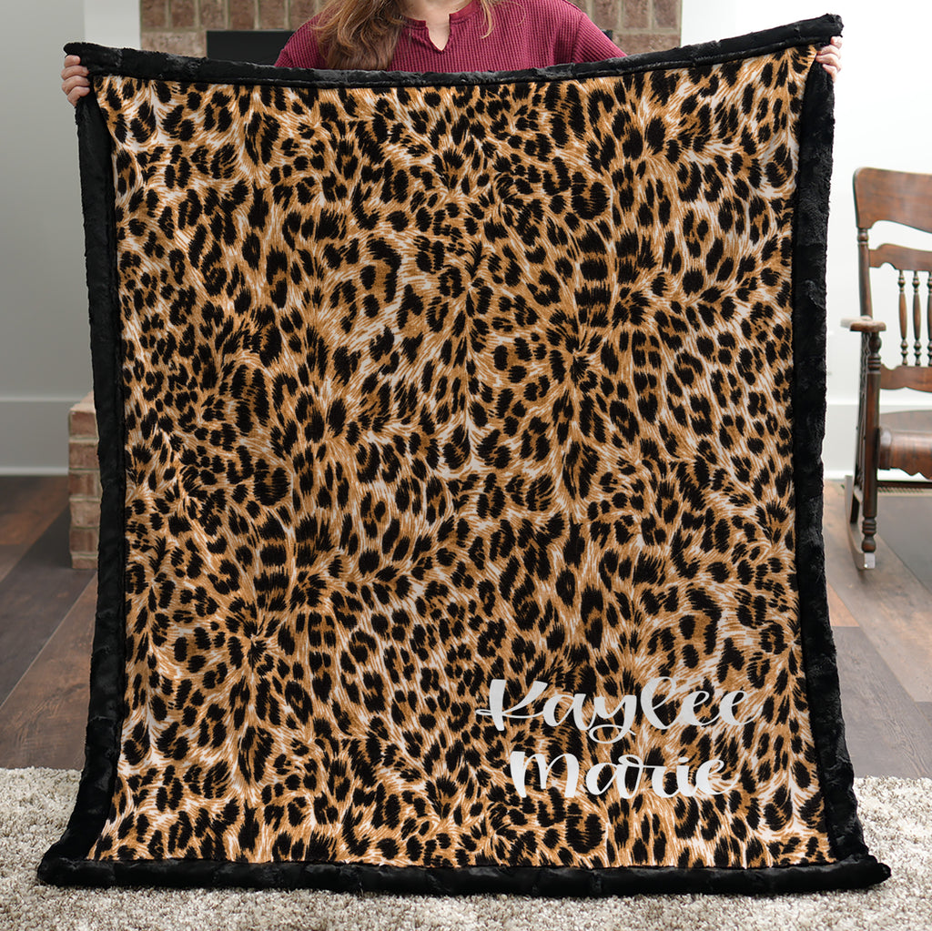Woman holding personalized leopard print minky blanket with black trim