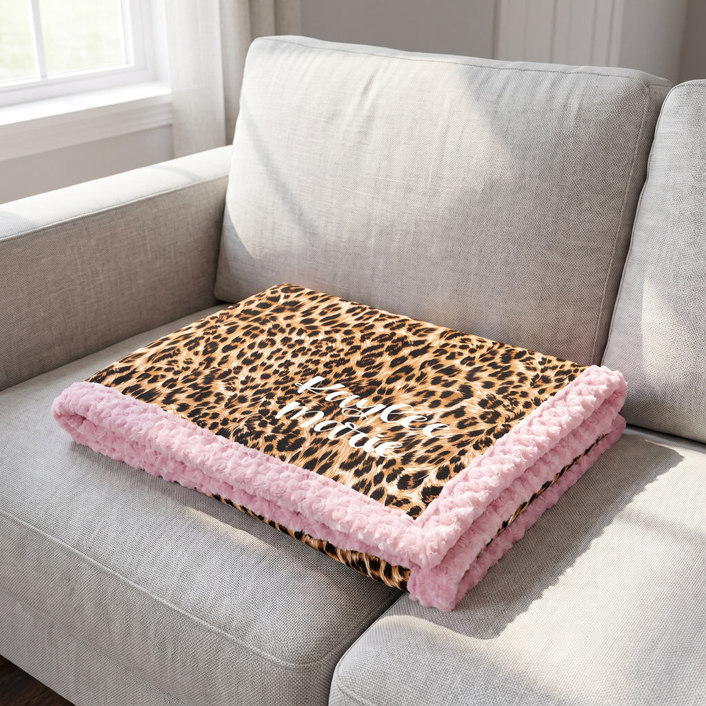 Personalized leopard print minky blanket with pink trim folded on couch